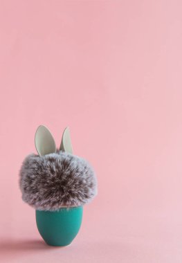 Parlak arka planda aquamarine yumurta standı tavşan tavşan kulakları ile Kürk topu. Paskalya minimal kavramı