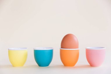 Pastel arka planda yumurta bardağının üzerinde duran bir kahverengi yumurta, kopya alanı. Paskalya minimal kavramı