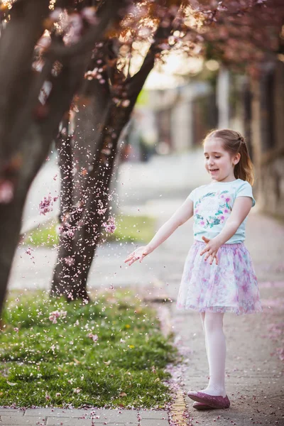 Outdoor portrait of happy child girl in spring park, cherry trees in blossom — Stock Photo, Image