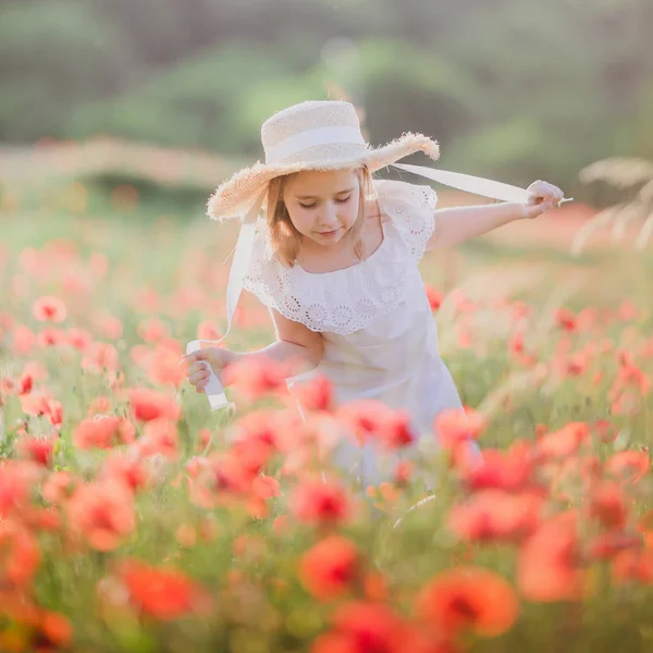 Kleines Mädchen mit Hut geht durch ein Mohnfeld — Stockfoto