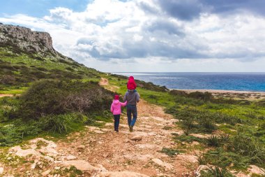 Baba ve iki kızı deniz boyunca yol boyunca yürürler. Deniz kenarında güzel bir vadi. Kıbrıs Rum Kesimi 'nde Deniz Burnu Ayia Napa