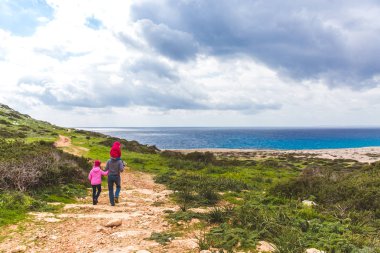 Baba ve iki kızı deniz boyunca yol boyunca yürürler. Deniz kenarında güzel bir vadi. Kıbrıs Rum Kesimi 'nde Deniz Burnu Ayia Napa
