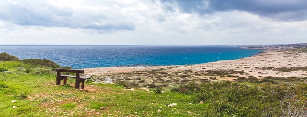 Bank deniz kıyısında duruyor. Denizin yanında güzel bir vadi. Kıbrıs Deniz Manzarası Ayia Napa