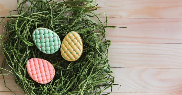 Bunte Ostereier-Plätzchen im Nest auf hellem Holzgrund — Stockfoto