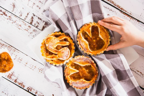 Kinder nehmen ein mit Puderzucker bestreutes Törtchen mit Pfirsichmarmelade — Stockfoto