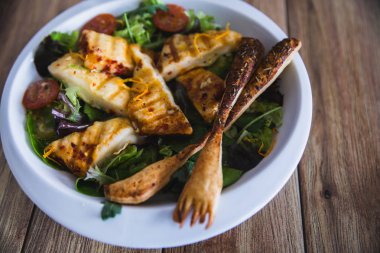 Izgara Halloumi Peynir salatası cadı domates ve ahşap arka planda beyaz tabakta marul. sağlıklı gıda