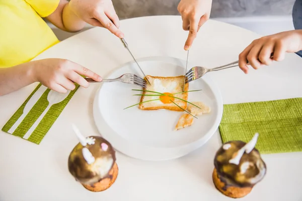 Two kids hands eat easter breakfast with cute bunny made of eggs in bread. Easter Cakes decorated with bunny ears - Traditional Kulich, Paska Easter Bread