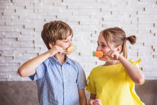Очаровательная девочка и мальчик держат красочные сладкие безе на палочке в пасхальный день — стоковое фото