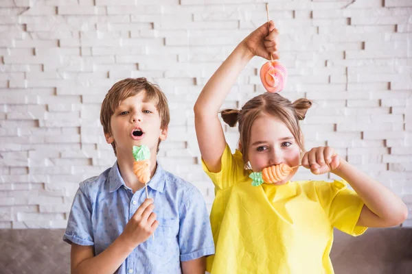 Adorable girl and boy holding colorful sweet meringues on a stick on Easter day — Stock Photo, Image