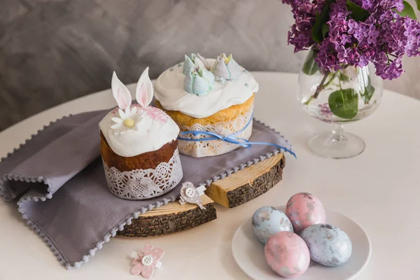 Velikonoční koláče na dřevěné zdobené králičí uši, vejce na vraku na výstupu, fialová na pozadí. -Tradiční Kulich, paska velikonoční chléb — Stock fotografie