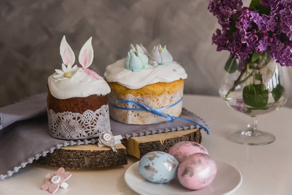 Osterkuchen auf Holz verziert mit Hasenohren, Eier auf dem Teller im Vordergrund, Flieder im Hintergrund. - traditionelles kulich, paska-Osterbrot — Stockfoto