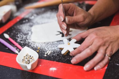 Kadın, Noel kurabiyelerini şekerli kartanesiyle süslüyor. Noel hediyesi, ev yapımı zencefilli çörek.