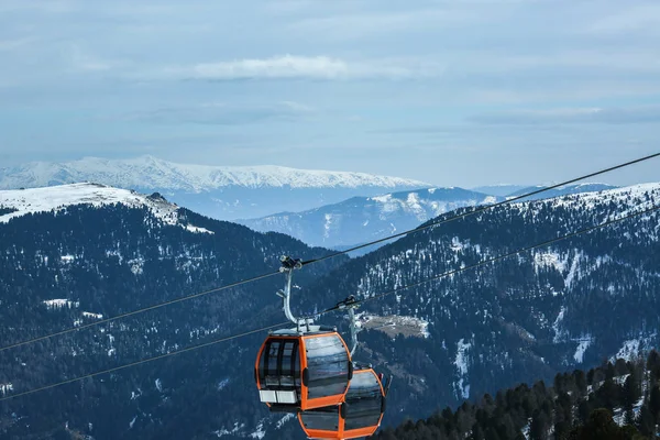 Orange gondola cabins of cableway lift on winter snowy mountains background beautiful scenery — Stock Photo, Image