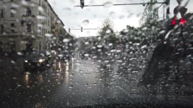 Geçen araba ile bir yol bakan bir pencereüzerinde yağmur düşer
