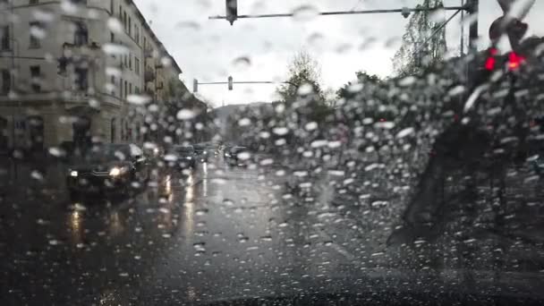 Regndroppar på ett fönster med utsikt över en väg med passerande bilar — Stockvideo