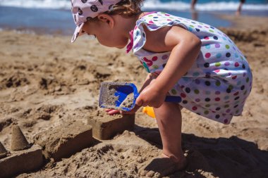 Sahilde kumdan kale yapma sevimli küçük kız