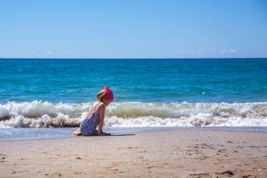 Güzel bir dalganın arka planında sahilde sırtı ile kız koltuklar