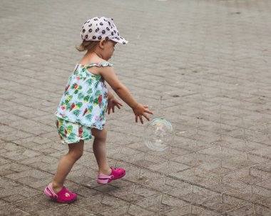 Pretty küçük kız yaz günü sokakta büyük kabarcıklar ile oynuyor