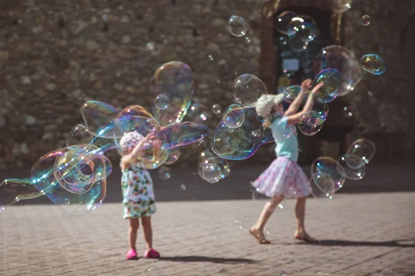 Draußen fliegen große Seifenblasen durch die Luft. Kinder spielen an Sommertagen im Hintergrund — Stockfoto