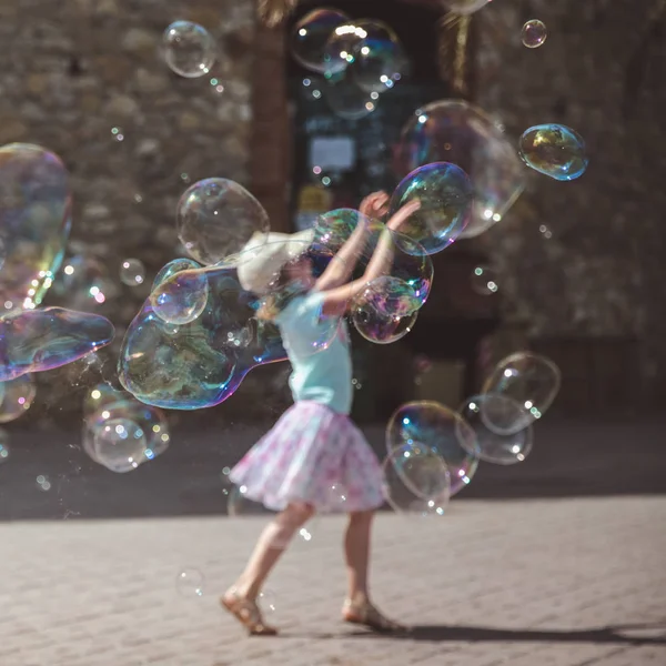 Draußen fliegen große Seifenblasen durch die Luft. Mädchen spielt im Hintergrund an einem Sommertag — Stockfoto