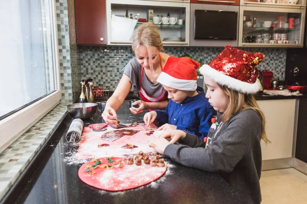 Счастливая семья матери и детей сын и дочь пекут пасту на Рождество — стоковое фото