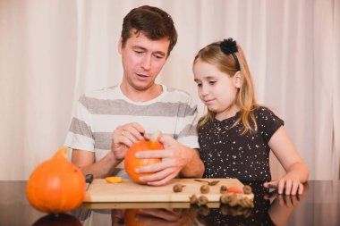 Cadılar Bayramınız Kutlu Olsun. Baba ve kızı evde Cadılar Bayramı için kabak oyma