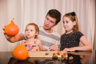 Cadılar Bayramınız Kutlu Olsun. Baba ve iki kızı evde Cadılar Bayramı için balkabağı oyma. Mutlu aile