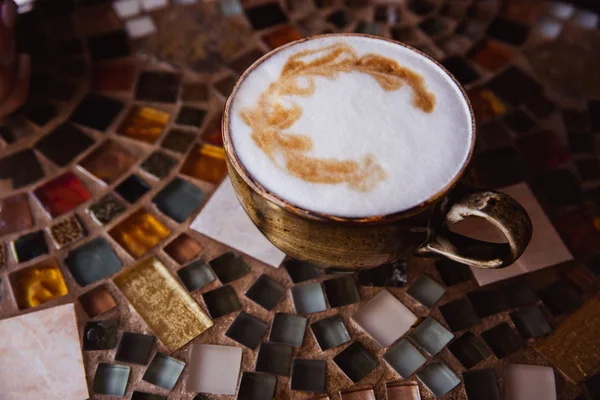 Filiżanka kawy cappuccino na kolorowym szklanym stole w kawiarni — Zdjęcie stockowe