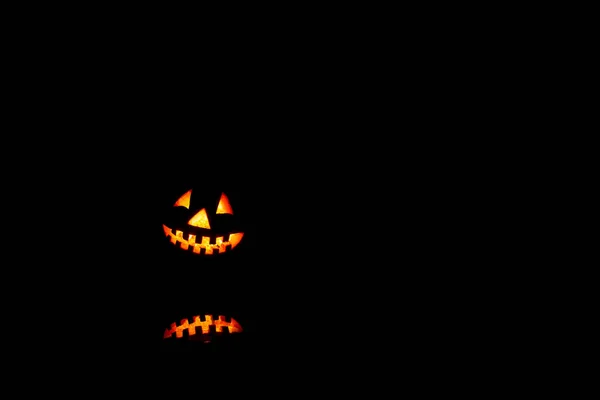 Noční dýně, úsměv a děsivé oči na večírek. Zblízka pohled na strašidelný Halloween starý Jack-lucerny s očima zářících v černém pozadí. — Stock fotografie