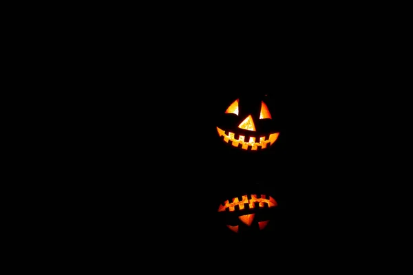 Halloween citrouilles sourire et les yeux effrayants pour la soirée. Vue rapprochée de l'effrayant Halloween vieux Jack-o-lanterne avec les yeux brillants à l'intérieur à fond noir . — Photo