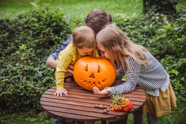 Cadılar Bayramınız Kutlu Olsun. Baba ve iki kızı Dışında Cadılar Bayramı için oyulmuş balkabağı içine bakmak.