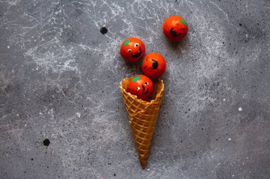 Waffle konisi, gri arka planda Cadılar Bayramı balkabaklarıyla doludur.