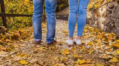 Kadınlar ve erkekler kurak sonbahar yaprakları üzerinde botlarını doğa parkında ve sonbahar mevsiminde giyerler.