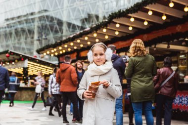 Tatlı küçük bir kız Budapeşte 'de kışın sokak pazarında adı Kurtoskalacs olan geleneksel bir Macar tatlısı yiyor.