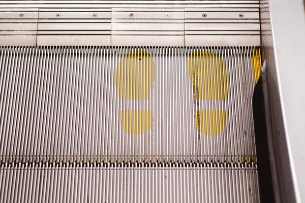 Pé sinal de ponto de impressão na escada rolante em amarelo para manter a distância durante a pandemia de Covid-19, cuidados de saúde , — Fotografia de Stock
