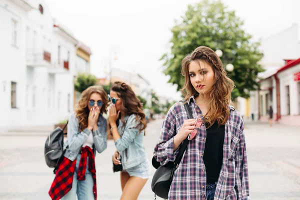 Filles jalouses chuchotant sur la troisième fille devant la caméra . — Photo