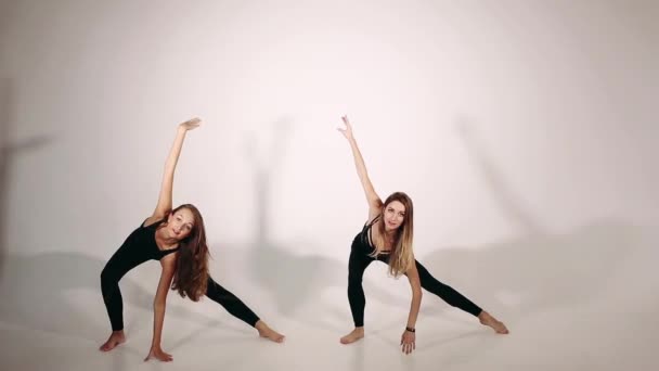 Dos mujeres en ropa deportiva negra haciendo ejercicio de yoga . — Vídeos de Stock