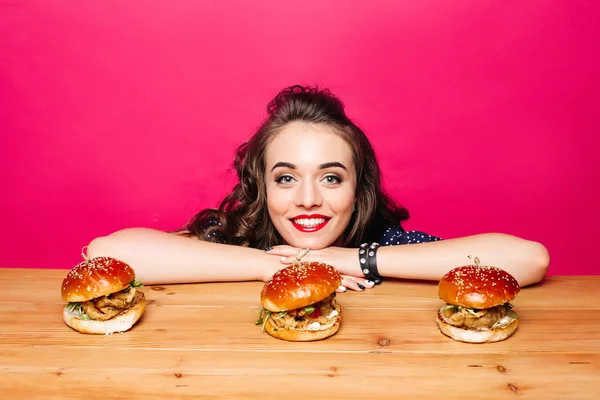 Feliz chica hermosa con peinado con tres hamburguesas en madera —  Fotos de Stock