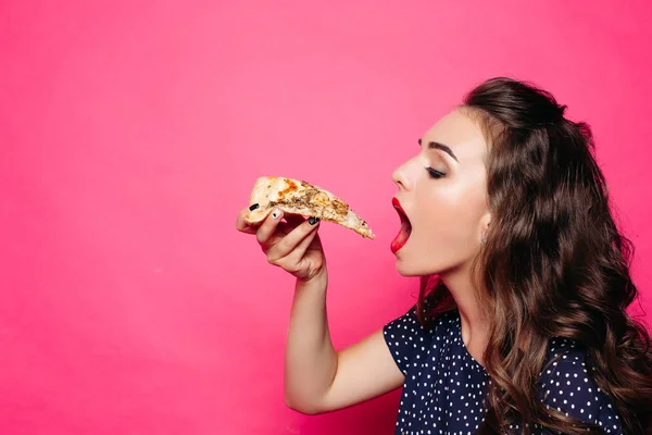 Piękna brunetka z falowane włosy jedzenie kawałek pizzy. — Zdjęcie stockowe