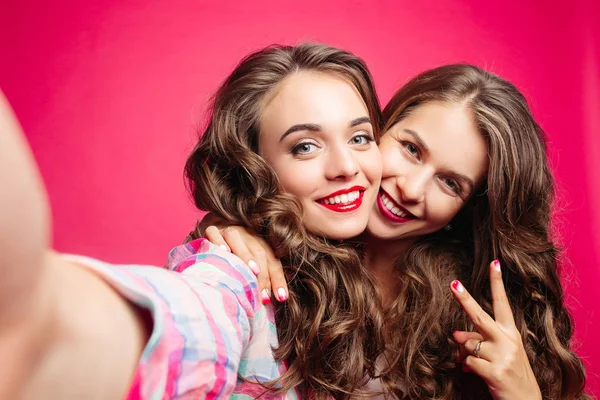 Self portrait of beautiful brunette girls in pink studio. — Stock Photo, Image