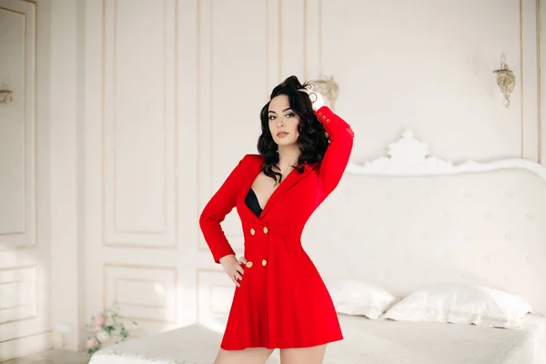 Sexy donna bruna in abito rosso in posa in camera da letto . — Foto Stock
