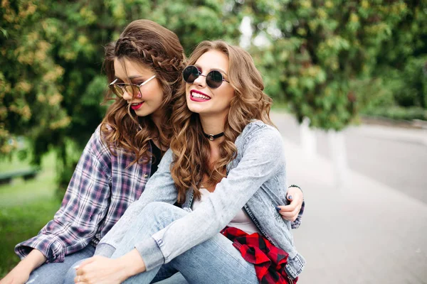 Casal de belas meninas adolescentes na moda em óculos de sol no parque . — Fotografia de Stock