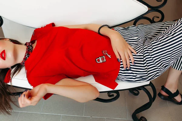 Menina bonita vestindo roupas da moda e lábios vermelhos, deitado e relaxante . — Fotografia de Stock