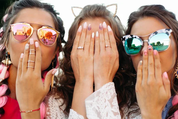 Trzy młode dziewczyny sobie w okulary, ukrywając twarz przez ręce z bliska. — Zdjęcie stockowe