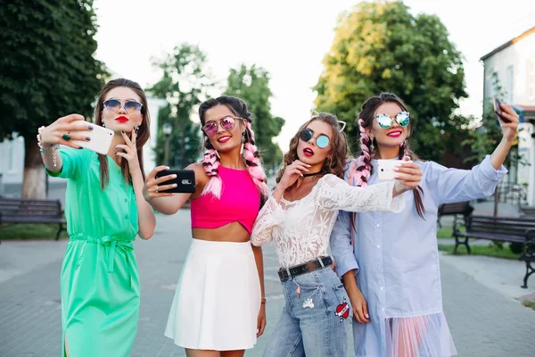 Cuatro mejores amigas de moda y magníficas con gafas, cada una posando haciendo selfies para redes sociales, se divierten. Mujeres en gafas de sol después de ir de compras y salón de belleza — Foto de Stock