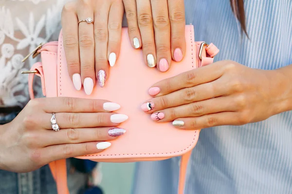 Two girls with design manicure holding leather pink bag.