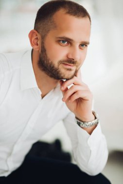 Çene elle tutarak ve kameraya bakarak kendine güvenen adam.