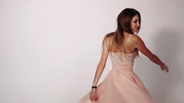 Trendy pastel pembe elbise sevimli ve çekici genç kız kestane rengi saçlı. Çok güzel modeli twirling ve Studio beyaz arka plan ile poz sallayarak alevlendi etekle döne döne.