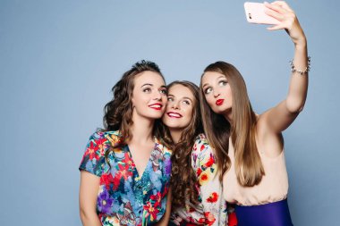 Trendy kıyafetler üzerinde mavi backgrou selfie alarak mutlu arkadaşlar