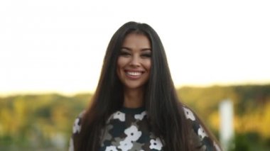 Mutlu ve güzel kameraya gülümseyen uzun saçlı esmer kız.